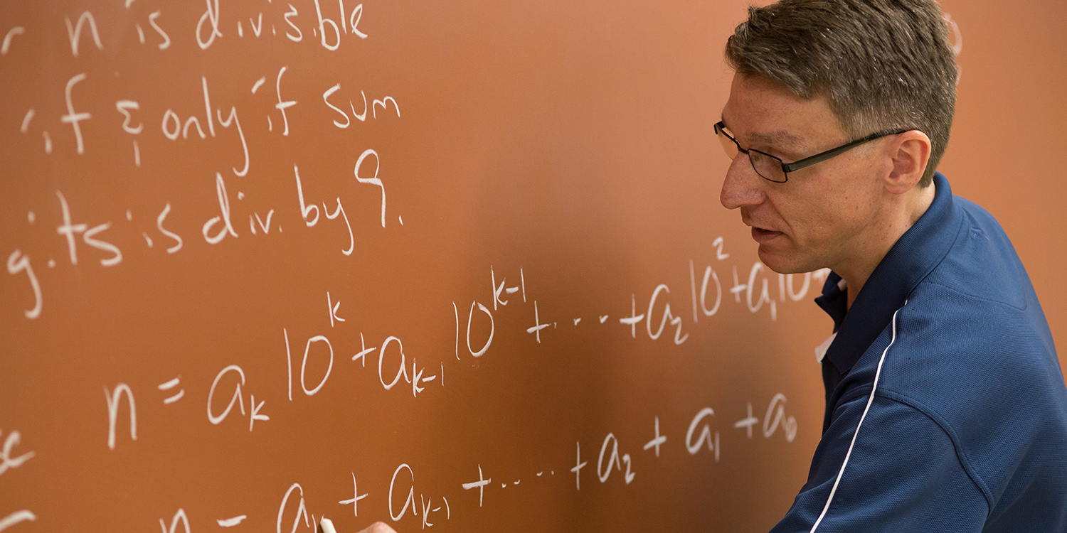 Math Professor Writing Formula On Chalkboard